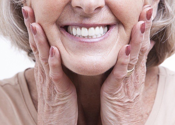 smiling elderly woman holding the sides of her face 