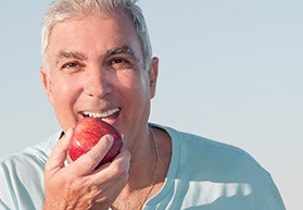 Man outside eating a red delicious apple