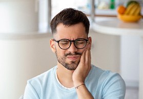 Man with black glasses experiencing toothache