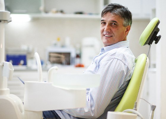 Older man sitting in dental chair and smiling
