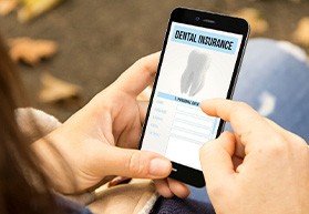 Patient looking at dental insurance form on phone outside