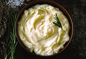 Bowl of mashed potatoes on wooden table