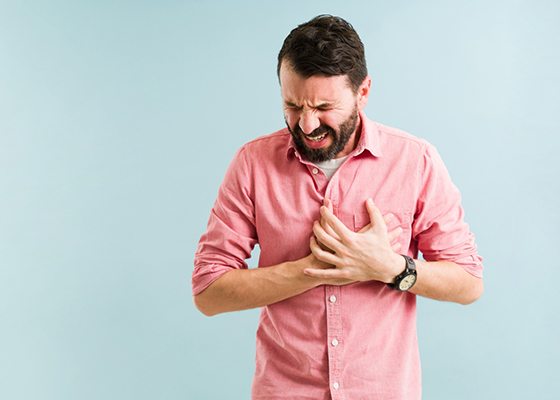 Man grimacing and clutching his heart