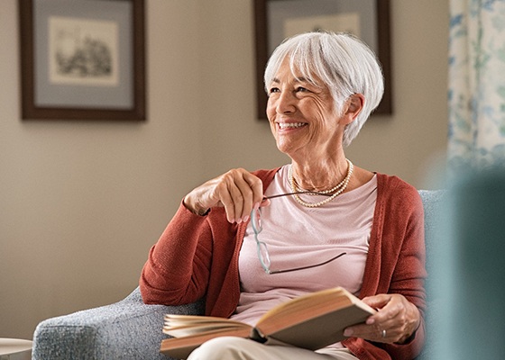 Senior woman smiling while reading at home