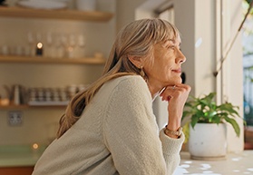 Senior woman smiling while looking out the window at home