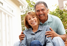 An older couple smiling together and enjoying their new and improved teeth