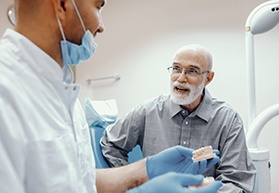 An older man listening closely as his dentist explains the benefits of dental implants