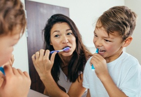 a parent brushing their teeth with their child