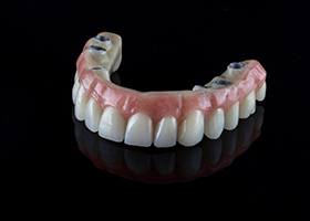 a real removable implant denture against a black background