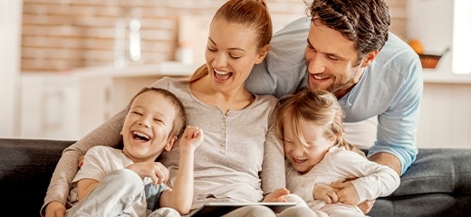 Family of four laughing on their couch