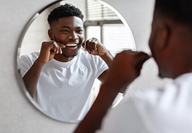 Patient smiling while flossing his teeth