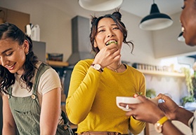 Friends smiling while eating meal together in kitchen