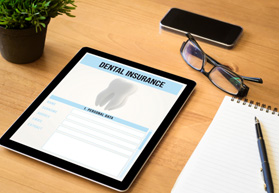 Dental insurance form on tablet next to notepad