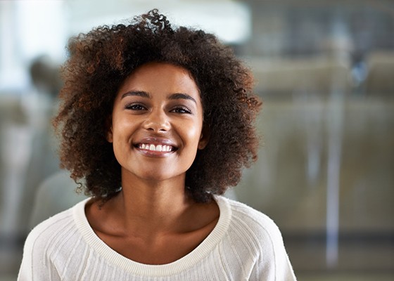 Woman in sweater smiling after visiting an emergency dentist in Annapolis, MD