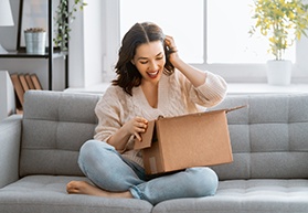Woman sitting on a couch with an open package