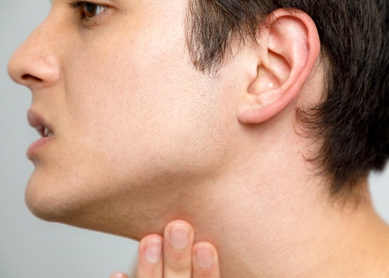 A young man with his hand on the base of his jaw showing the temporomandibular joint