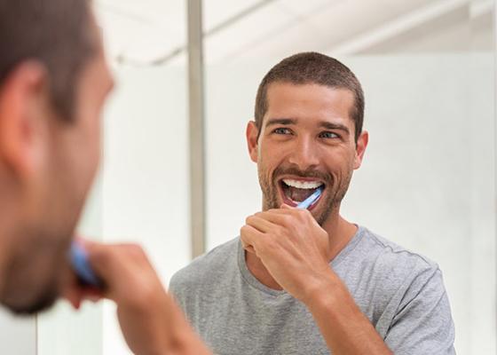 Man caring for veneers in Annapolis by brushing his teeth