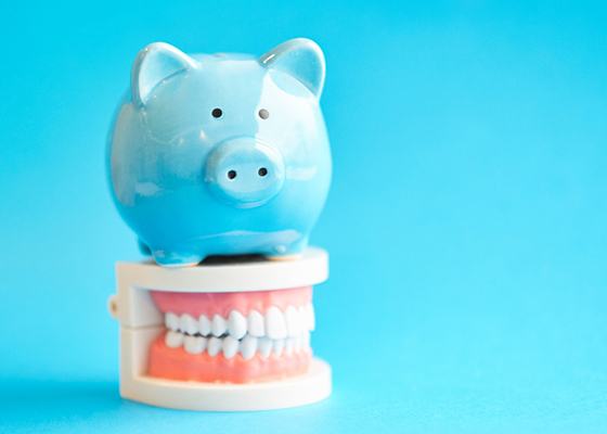 Piggy bank on model teeth representing the cost of veneers in Annapolis