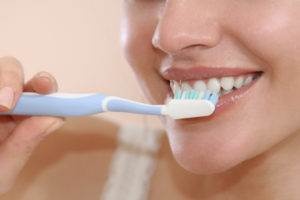 woman smiling while brushing her teeth