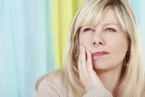 blonde woman holding jaw in pain