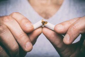 man breaking cigarette in half 