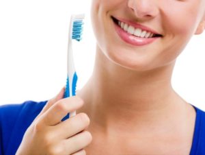 Woman holding a toothbrush at emergency dentist in Annapolis.