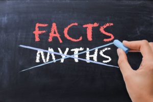 person crossing out "myths" on a chalkboard and writing "facts" in its place