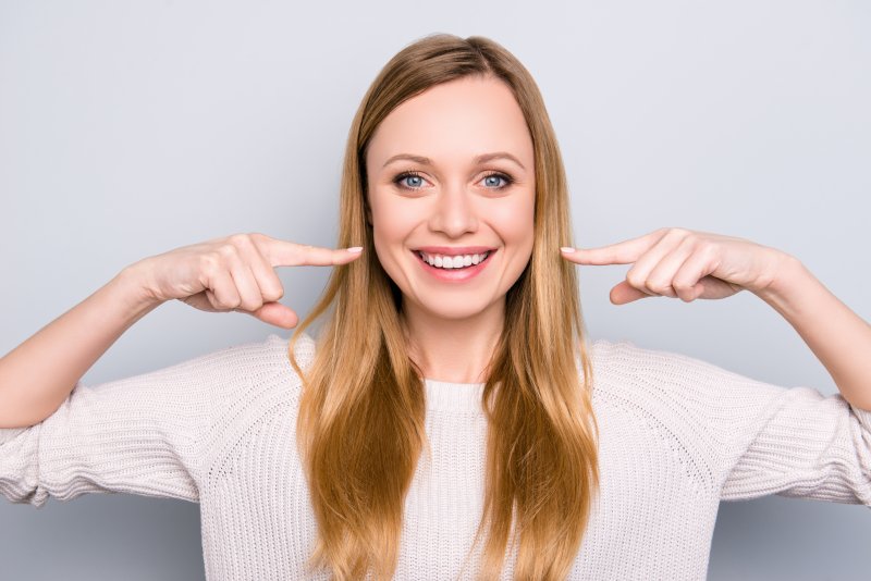 Woman pointing to her straight, white smile