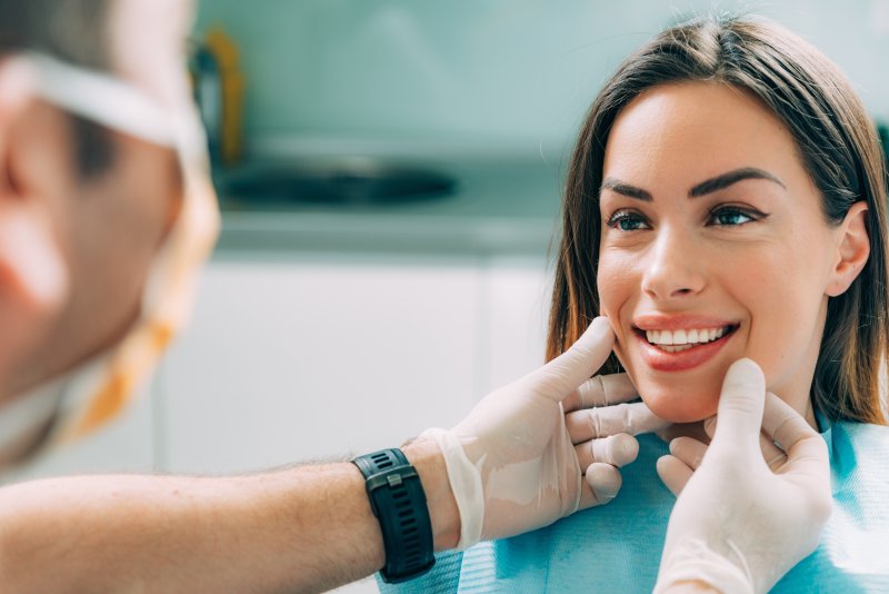 Cosmetic dentist checking female patient’s smile