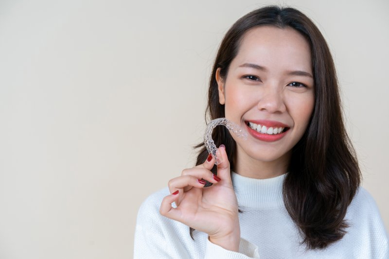 Young woman holding her Invisalign aligner