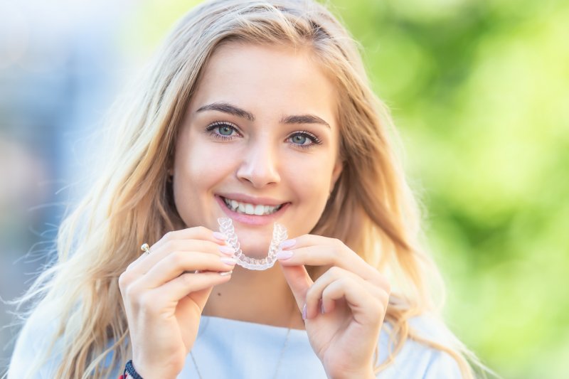 Young woman holding her Invisalign aligner