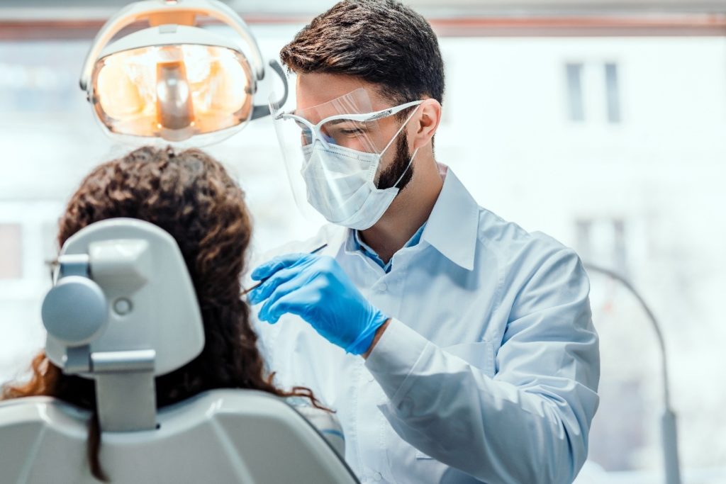dentist putting dental filling on female patients’ tooth 