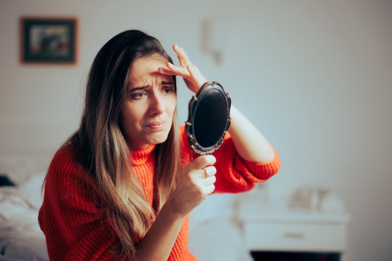 A woman looking in the mirror after dermal fillers