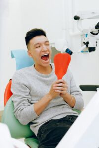 Smiling man in dentist’s chair looking in mirror