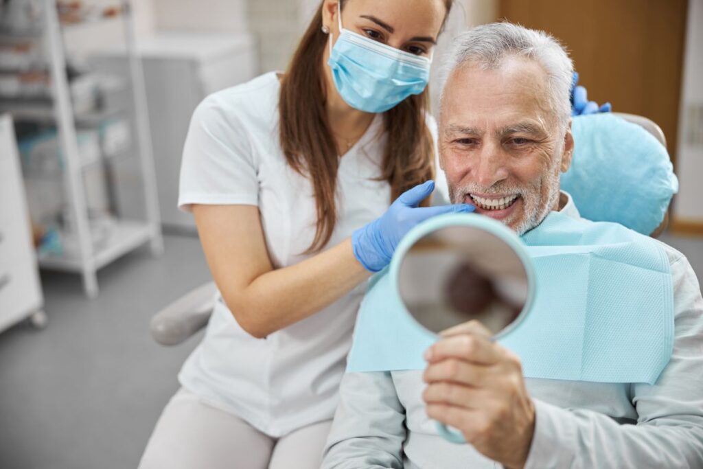 A man and his dentist looking at his dental implants in a mirror